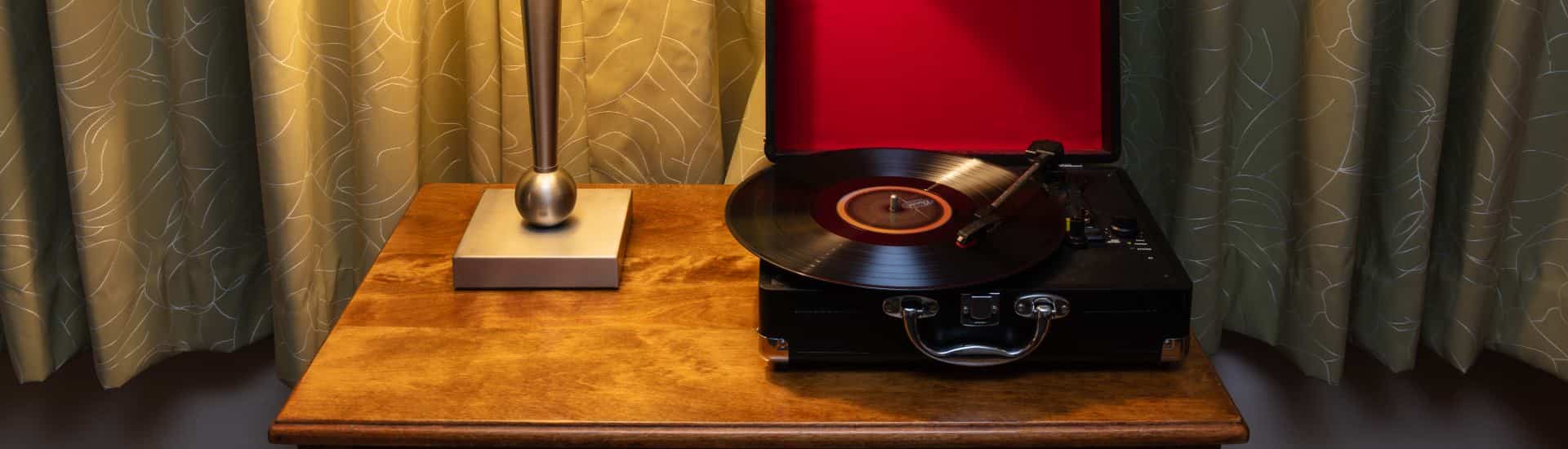 Close up view of a record player in a black leather case on top of wooden desk