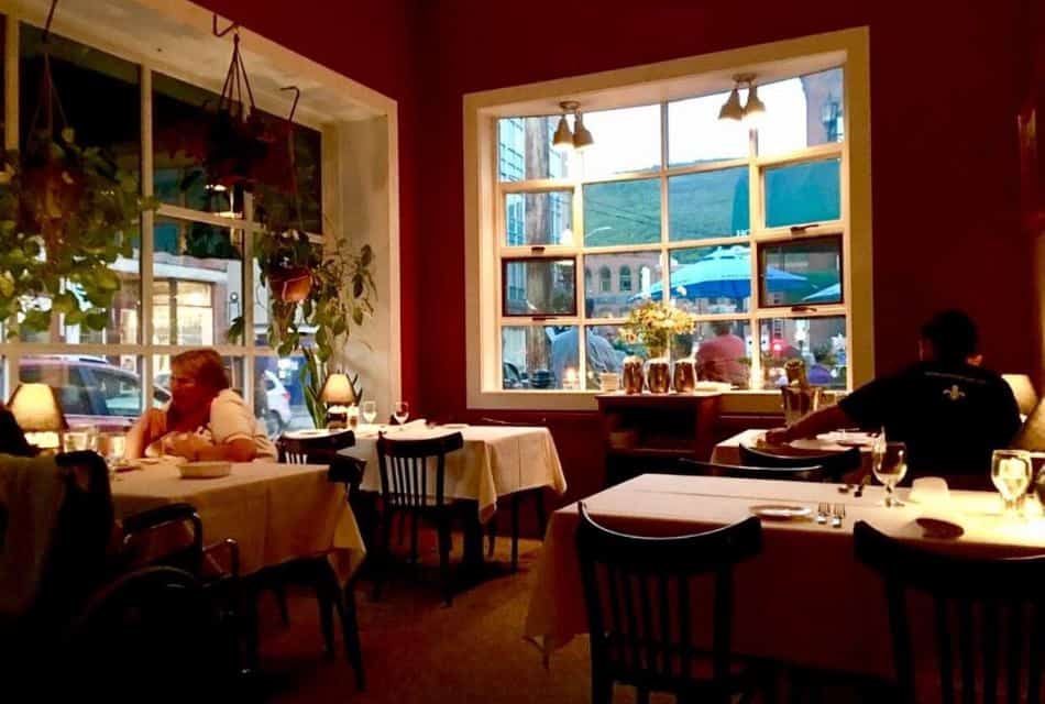 Local restaurant's dining room with red walls, tables with white tablecloths, and black chairs