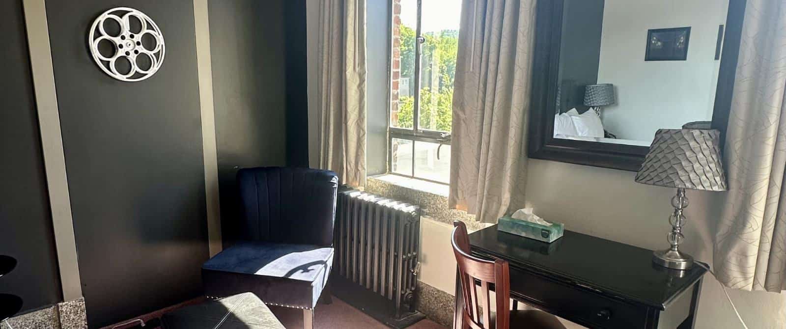 Bedroom with dark gray walls, dark blue upholstered chair, and desk with chair