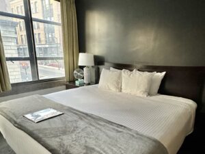 Bedroom with dark gray walls, dark wooden headboard, white bedding, and dark wooden nightstands with lamps