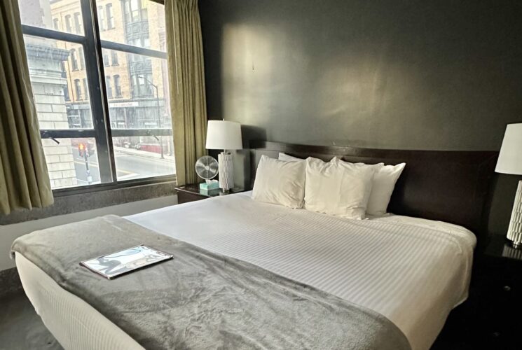 Bedroom with dark gray walls, dark wooden headboard, white bedding, and dark wooden nightstands with lamps