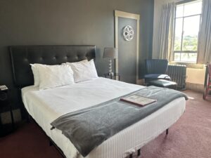 Bedroom with dark gray walls, black leather headboard, white bedding, and black wooden nightstands with lamps