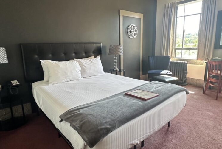 Bedroom with dark gray walls, black leather headboard, white bedding, and black wooden nightstands with lamps