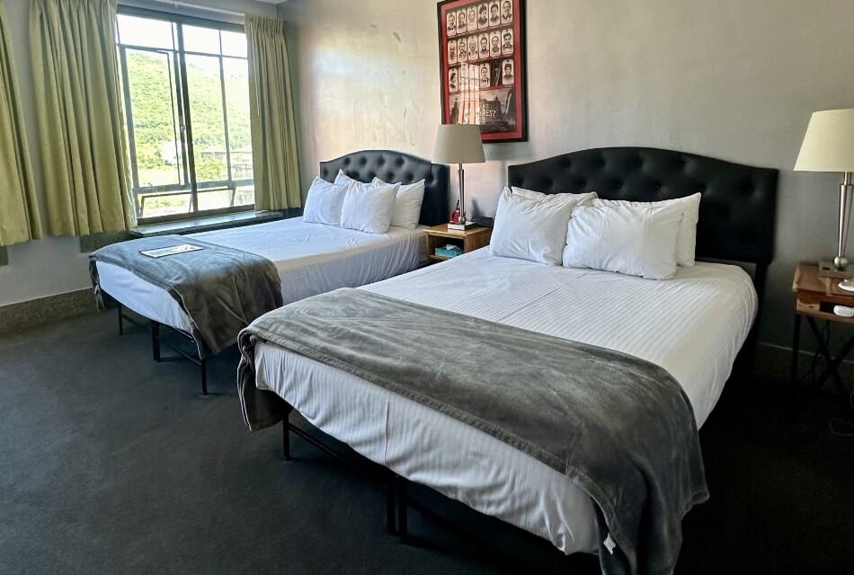 Bedroom with light colored walls, gray carpeting, two beds with gray and white bedding