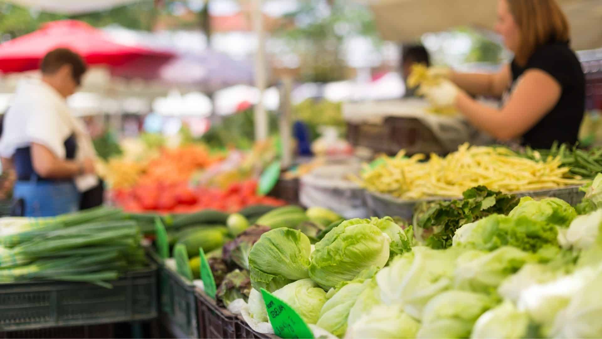 people shopping at a farmers market. lens focused on lettuce.