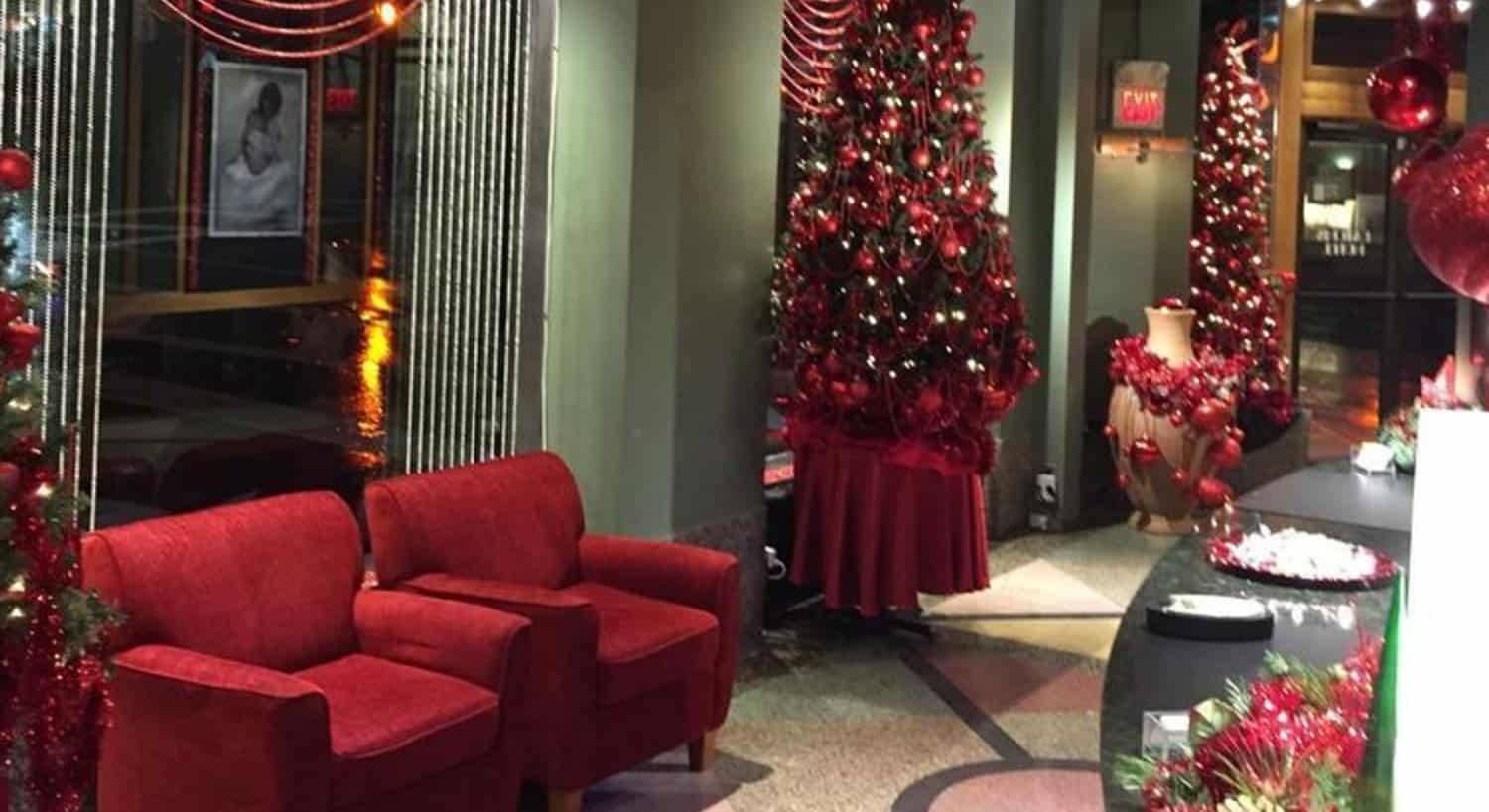 Front lobby of hotel with green walls, art deco designed flooring, and red Christmas decorations